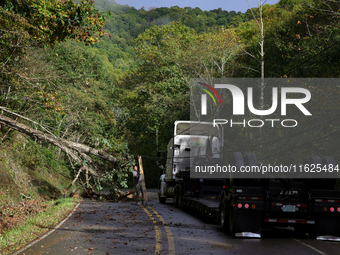 A truck driver works to remove entangled wires after passing through a damaged roadway in Whitetop, Virginia on September 30, 2024 after Hur...