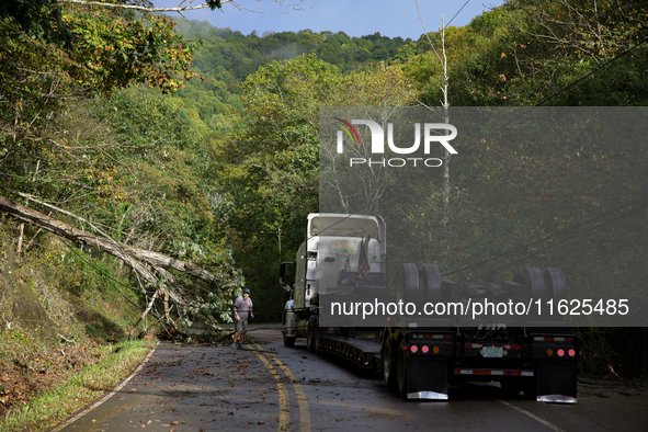 A truck driver works to remove entangled wires after passing through a damaged roadway in Whitetop, Virginia on September 30, 2024 after Hur...