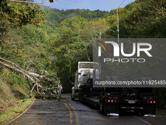 A truck driver works to remove entangled wires after passing through a damaged roadway in Whitetop, Virginia on September 30, 2024 after Hur...