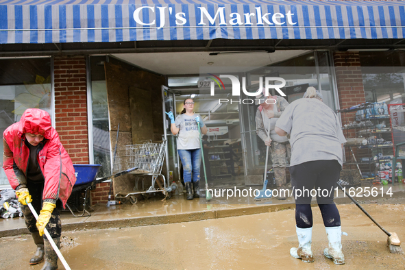 Tricia Hart, co-owner of CJ's Market in Lansing, North Carolina, left in pink, cleans up storm damage on September 30, 2024 after Hurricane...