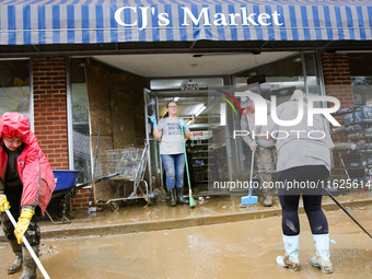 Tricia Hart, co-owner of CJ's Market in Lansing, North Carolina, left in pink, cleans up storm damage on September 30, 2024 after Hurricane...