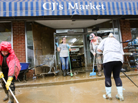 Tricia Hart, co-owner of CJ's Market in Lansing, North Carolina, left in pink, cleans up storm damage on September 30, 2024 after Hurricane...