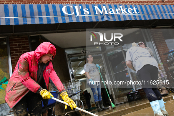 Tricia Hart, co-owner of CJ's Market in Lansing, North Carolina, left in pink, cleans up storm damage on September 30, 2024 after Hurricane...