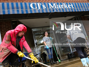 Tricia Hart, co-owner of CJ's Market in Lansing, North Carolina, left in pink, cleans up storm damage on September 30, 2024 after Hurricane...