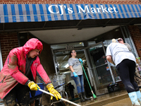 Tricia Hart, co-owner of CJ's Market in Lansing, North Carolina, left in pink, cleans up storm damage on September 30, 2024 after Hurricane...