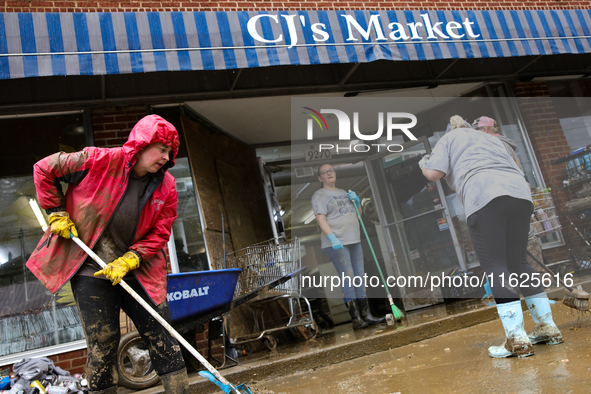 Tricia Hart, co-owner of CJ's Market in Lansing, North Carolina, left in pink, cleans up storm damage on September 30, 2024 after Hurricane...