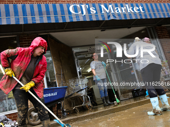 Tricia Hart, co-owner of CJ's Market in Lansing, North Carolina, left in pink, cleans up storm damage on September 30, 2024 after Hurricane...