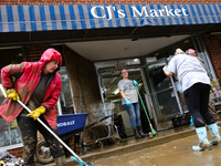 Tricia Hart, co-owner of CJ's Market in Lansing, North Carolina, left in pink, cleans up storm damage on September 30, 2024 after Hurricane...