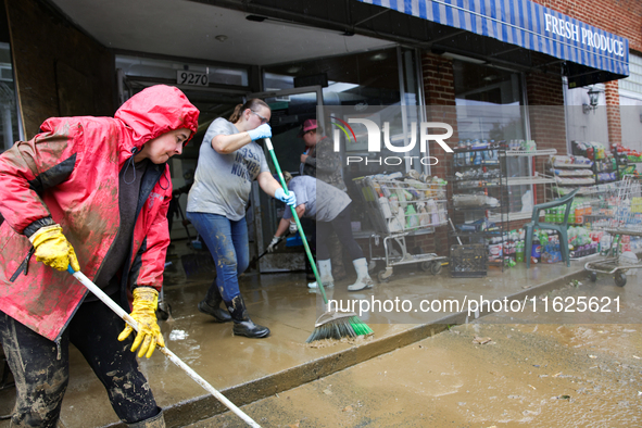 Tricia Hart, co-owner of CJ's Market in Lansing, North Carolina, left in pink, cleans up storm damage on September 30, 2024 after Hurricane...