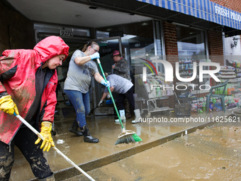 Tricia Hart, co-owner of CJ's Market in Lansing, North Carolina, left in pink, cleans up storm damage on September 30, 2024 after Hurricane...