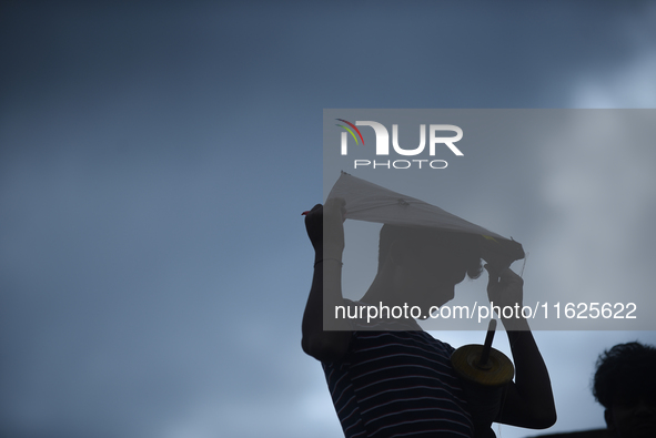 A silhouette view of a young boy flying a kite on the roof of a house in Kirtipur, Kathmandu, Nepal, on September 15, 2024. People fly kites...