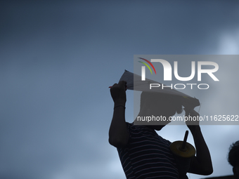 A silhouette view of a young boy flying a kite on the roof of a house in Kirtipur, Kathmandu, Nepal, on September 15, 2024. People fly kites...