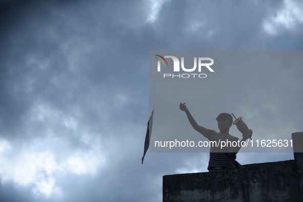 A silhouette view of a young boy flying a kite on the roof of a house in Kirtipur, Kathmandu, Nepal, on September 15, 2024. People fly kites...