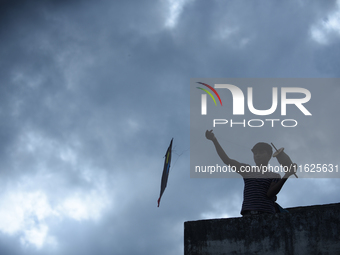 A silhouette view of a young boy flying a kite on the roof of a house in Kirtipur, Kathmandu, Nepal, on September 15, 2024. People fly kites...