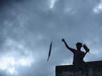 A silhouette view of a young boy flying a kite on the roof of a house in Kirtipur, Kathmandu, Nepal, on September 15, 2024. People fly kites...