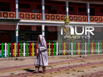 A woman walks after casting her vote in the third phase of Assembly elections in Handwara, Jammu and Kashmir, India, on October 1, 2024. (