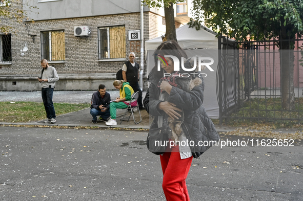 A resident of a multi-storey building damaged by a Russian airstrike carries a dog in her arms in Zaporizhzhia, Ukraine, on September 29, 20...