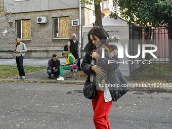 A resident of a multi-storey building damaged by a Russian airstrike carries a dog in her arms in Zaporizhzhia, Ukraine, on September 29, 20...