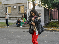 A resident of a multi-storey building damaged by a Russian airstrike carries a dog in her arms in Zaporizhzhia, Ukraine, on September 29, 20...