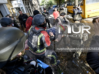 Rescuers carry a local resident, Yuliia, who is freed from the rubble of a multi-storey residential building damaged by a Russian KAB, to an...