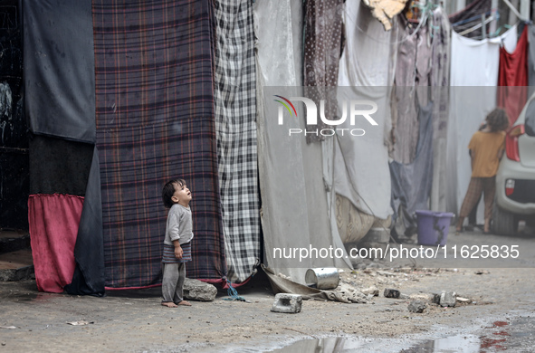 Palestinian displaced children react in front of their tent during rainfall in Deir al-Balah, central Gaza Strip, on September 1, 2024, amid...