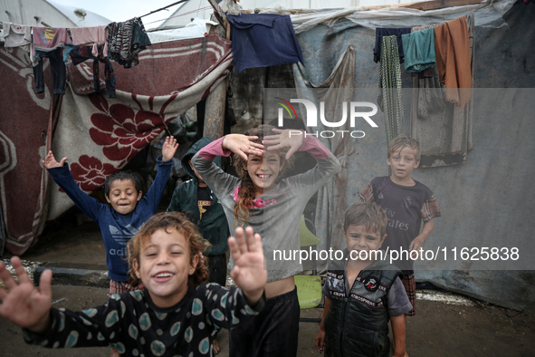 Palestinian displaced children react in front of their tent during rainfall in Deir al-Balah, central Gaza Strip, on September 1, 2024, amid...