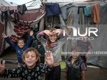 Palestinian displaced children react in front of their tent during rainfall in Deir al-Balah, central Gaza Strip, on September 1, 2024, amid...