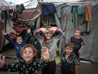 Palestinian displaced children react in front of their tent during rainfall in Deir al-Balah, central Gaza Strip, on September 1, 2024, amid...