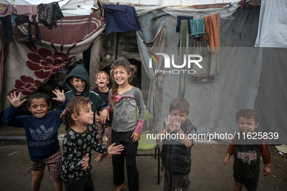 Palestinian displaced children react in front of their tent during rainfall in Deir al-Balah, central Gaza Strip, on September 1, 2024, amid...