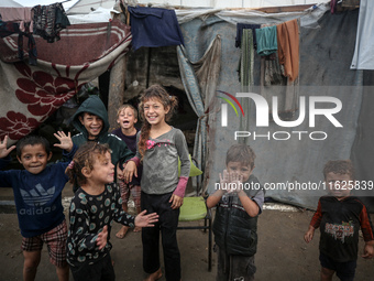 Palestinian displaced children react in front of their tent during rainfall in Deir al-Balah, central Gaza Strip, on September 1, 2024, amid...