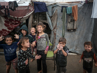 Palestinian displaced children react in front of their tent during rainfall in Deir al-Balah, central Gaza Strip, on September 1, 2024, amid...