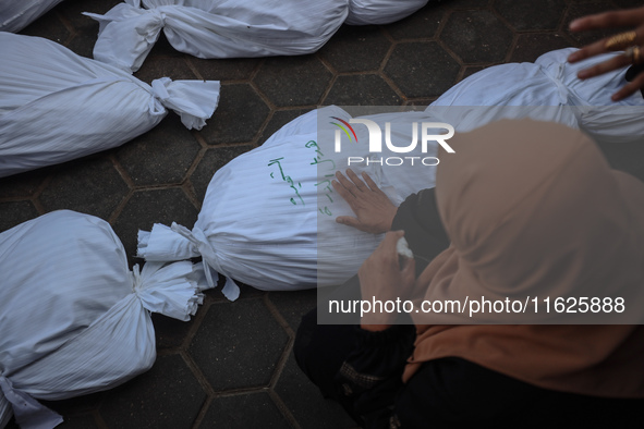 Relatives of Palestinians who are killed following the Israeli attack on the Nuseirat refugee camp mourn after the bodies are transferred to...