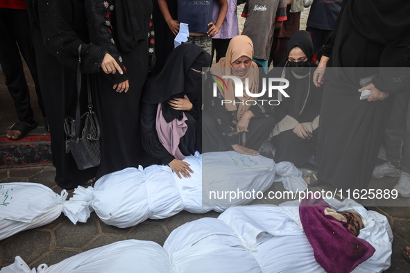 Relatives of Palestinians who are killed following the Israeli attack on the Nuseirat refugee camp mourn after the bodies are transferred to...