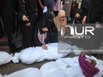 Relatives of Palestinians who are killed following the Israeli attack on the Nuseirat refugee camp mourn after the bodies are transferred to...