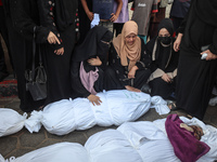 Relatives of Palestinians who are killed following the Israeli attack on the Nuseirat refugee camp mourn after the bodies are transferred to...