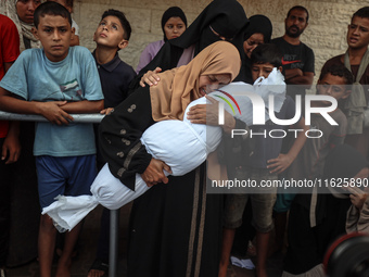 Relatives of Palestinians who are killed following the Israeli attack on the Nuseirat refugee camp mourn after the bodies are transferred to...