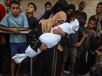 Relatives of Palestinians who are killed following the Israeli attack on the Nuseirat refugee camp mourn after the bodies are transferred to...