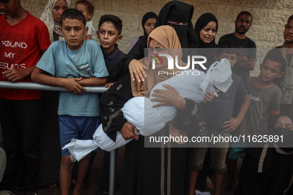 Relatives of Palestinians who are killed following the Israeli attack on the Nuseirat refugee camp mourn after the bodies are transferred to...