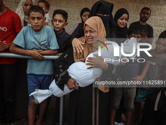 Relatives of Palestinians who are killed following the Israeli attack on the Nuseirat refugee camp mourn after the bodies are transferred to...