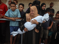 Relatives of Palestinians who are killed following the Israeli attack on the Nuseirat refugee camp mourn after the bodies are transferred to...