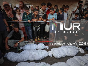 Relatives of Palestinians who are killed following the Israeli attack on the Nuseirat refugee camp mourn after the bodies are transferred to...