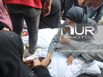 Relatives of Palestinians who are killed following the Israeli attack on the Nuseirat refugee camp mourn after the bodies are transferred to...