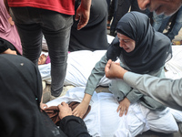 Relatives of Palestinians who are killed following the Israeli attack on the Nuseirat refugee camp mourn after the bodies are transferred to...