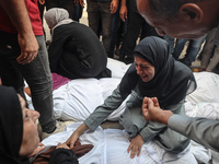 Relatives of Palestinians who are killed following the Israeli attack on the Nuseirat refugee camp mourn after the bodies are transferred to...