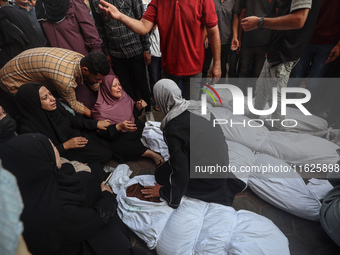 Relatives of Palestinians who are killed following the Israeli attack on the Nuseirat refugee camp mourn after the bodies are transferred to...