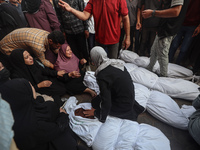 Relatives of Palestinians who are killed following the Israeli attack on the Nuseirat refugee camp mourn after the bodies are transferred to...