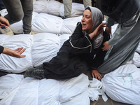 Relatives of Palestinians who are killed following the Israeli attack on the Nuseirat refugee camp mourn after the bodies are transferred to...