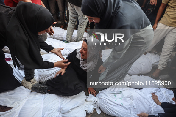 Relatives of Palestinians who are killed following the Israeli attack on the Nuseirat refugee camp mourn after the bodies are transferred to...