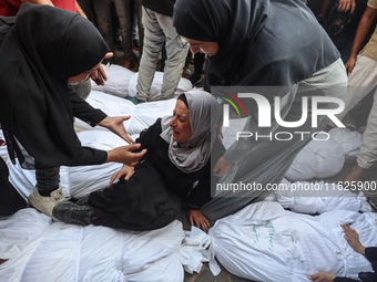 Relatives of Palestinians who are killed following the Israeli attack on the Nuseirat refugee camp mourn after the bodies are transferred to...