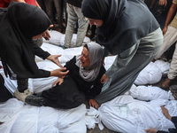 Relatives of Palestinians who are killed following the Israeli attack on the Nuseirat refugee camp mourn after the bodies are transferred to...